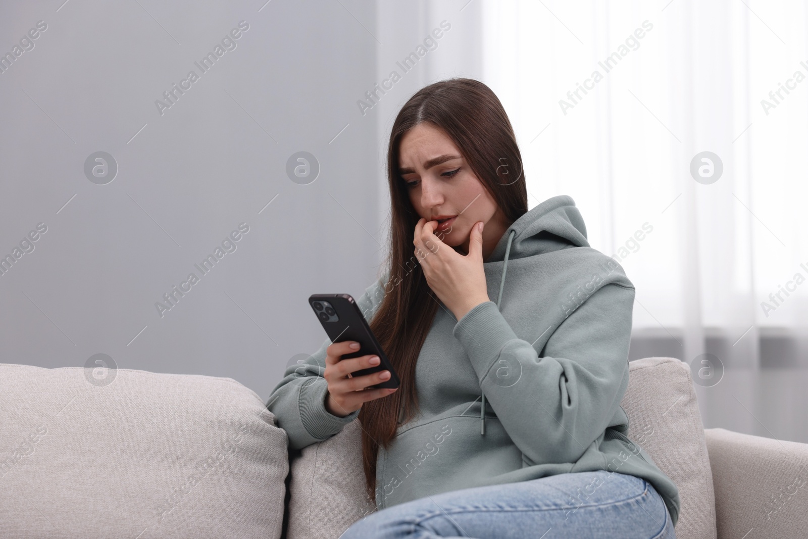 Photo of Depressed woman calling hotline for mental health help on sofa at home. Space for text