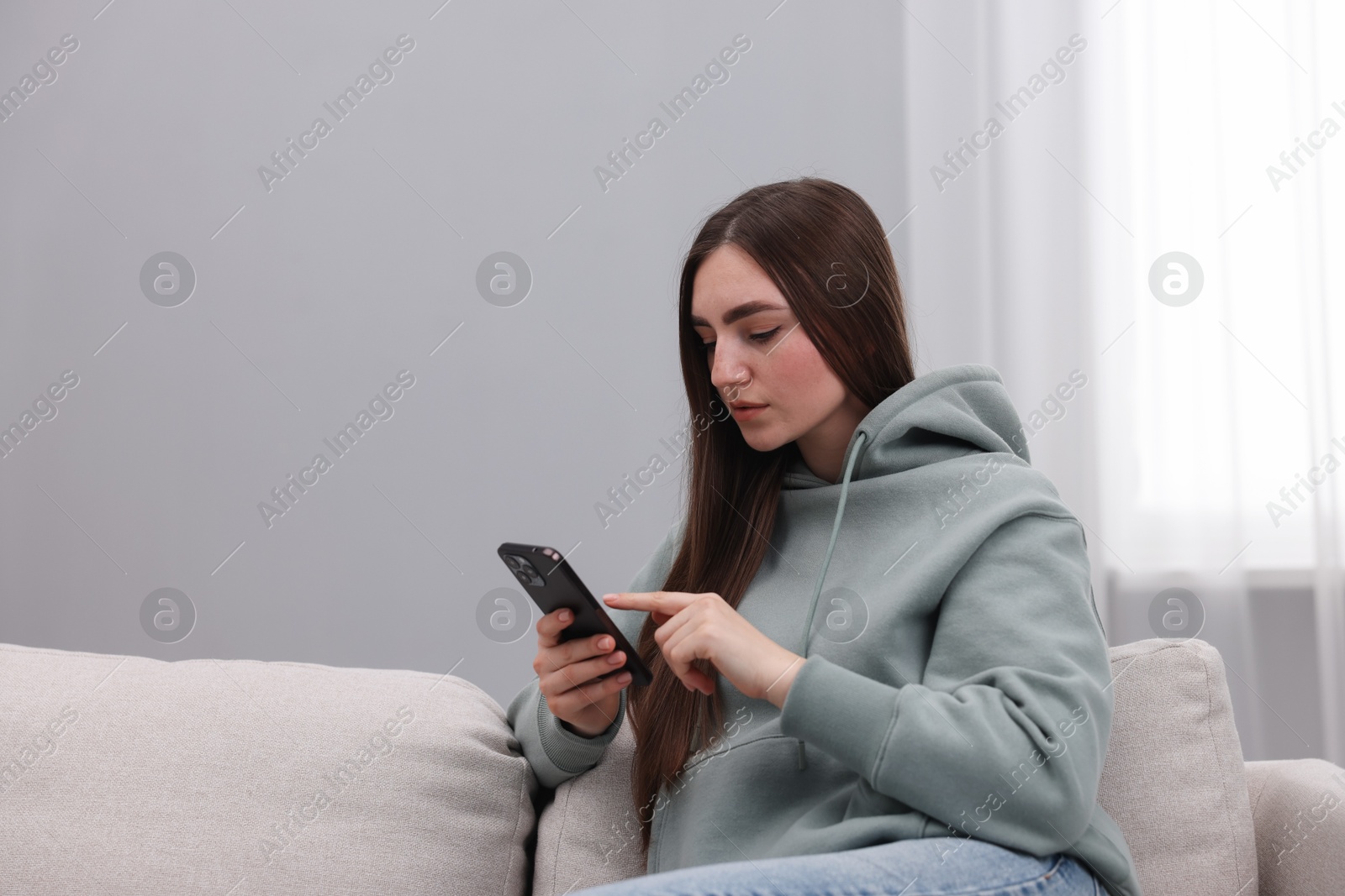 Photo of Depressed woman calling hotline for mental health help on sofa at home. Space for text