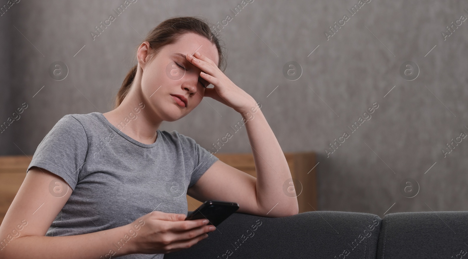 Photo of Depressed woman calling hotline for mental health help on sofa at home. Space for text