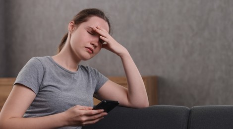 Photo of Depressed woman calling hotline for mental health help on sofa at home. Space for text