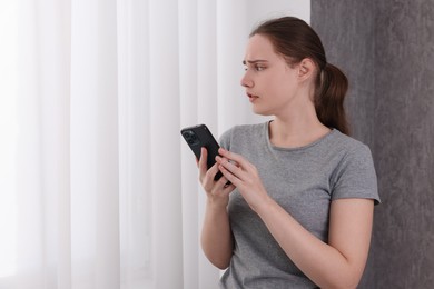 Photo of Stressed woman calling hotline for mental health help near window at home. Space for text