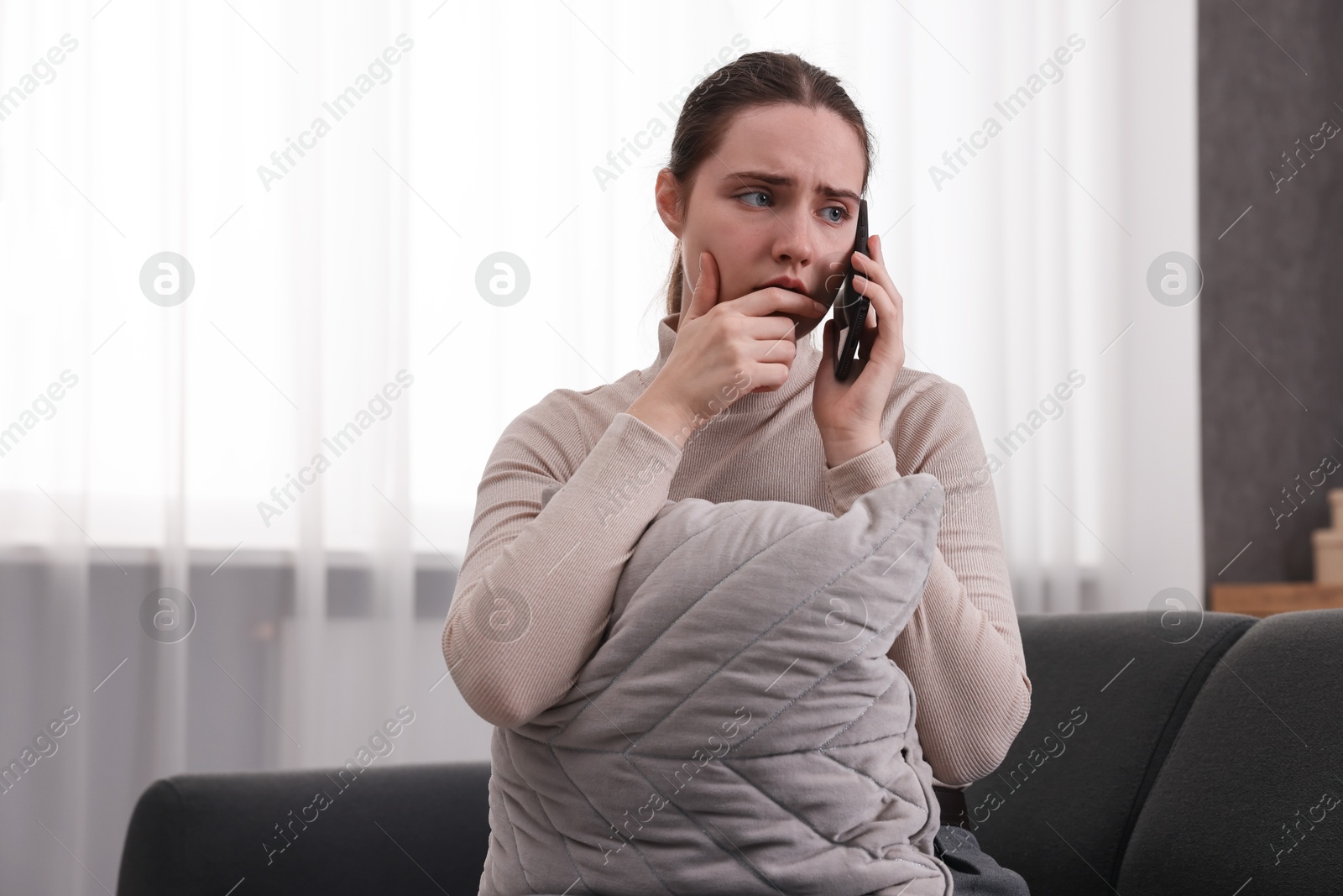 Photo of Depressed woman calling hotline for mental health help on sofa at home