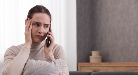 Stressed woman calling hotline for mental health help at home. Space for text