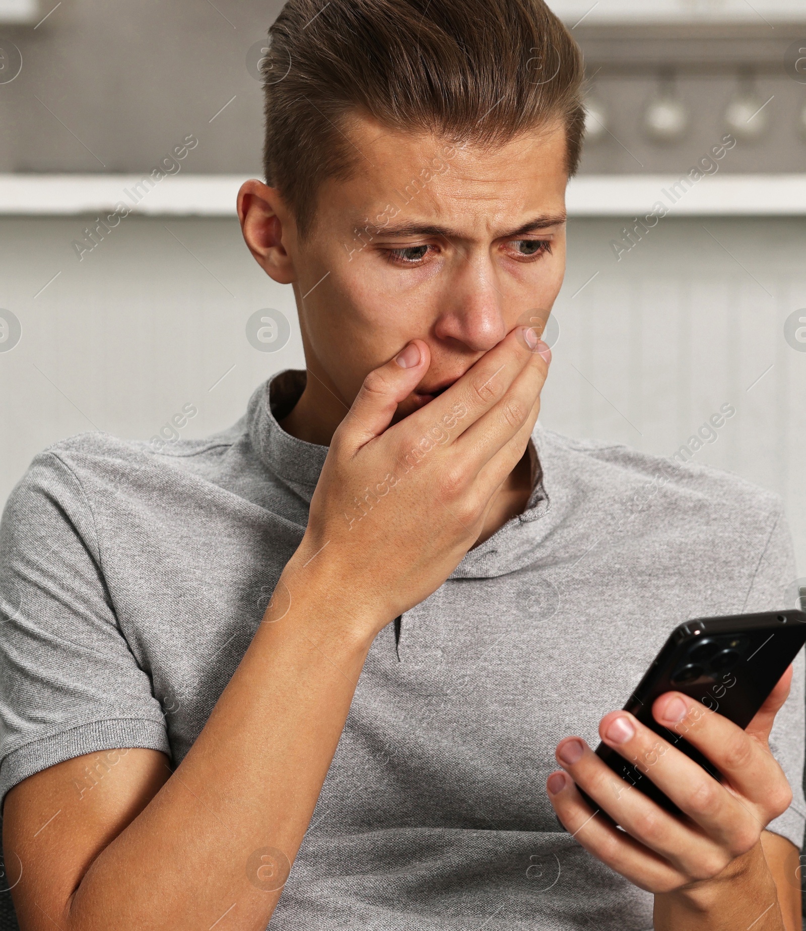 Photo of Worried man going to call hotline for mental health help on sofa in kitchen. Need for talk