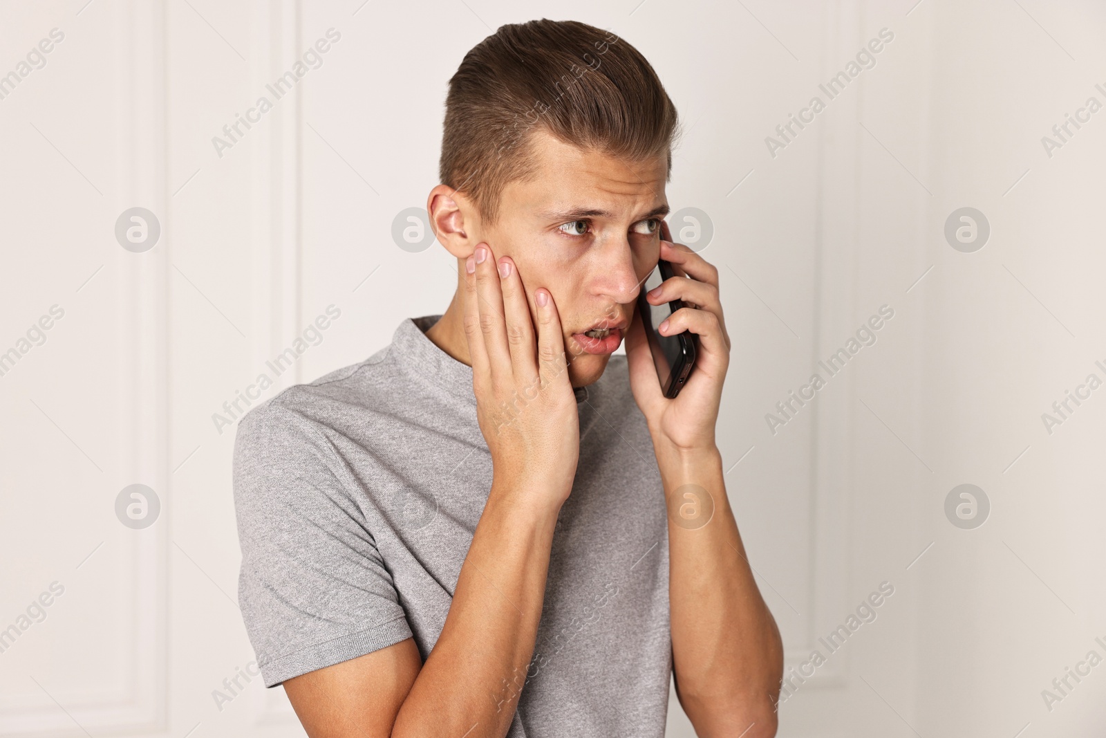 Photo of Stressed man calling hotline for mental health help indoors