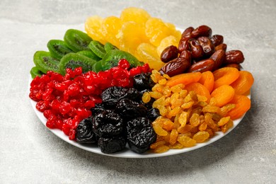 Photo of Mix of different dried fruits on gray textured table, closeup