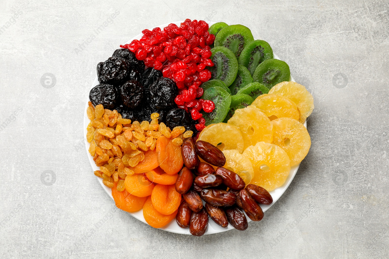 Photo of Mix of different dried fruits on gray textured table, top view