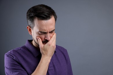 Sad man crying on grey background, space for text