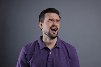 Portrait of sad man crying on grey background