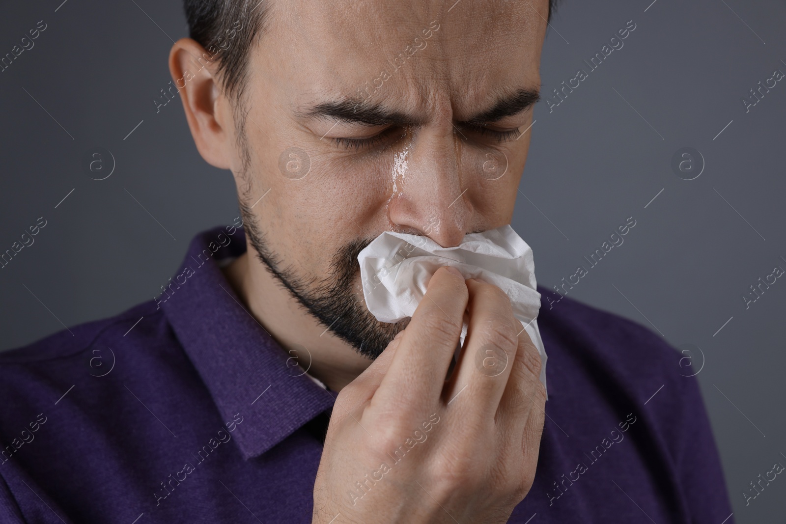 Photo of Sad man with paper tissue crying on grey background