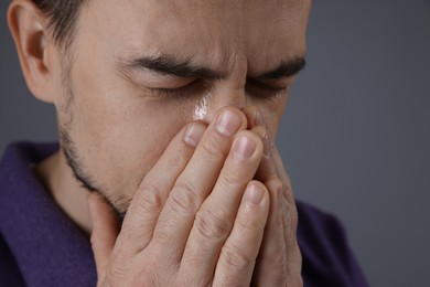 Sad man crying on grey background, closeup