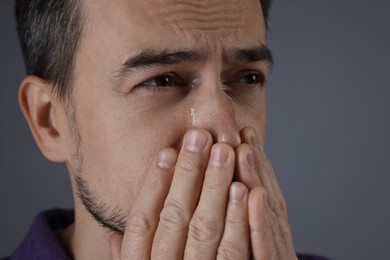 Photo of Sad man crying on grey background, closeup