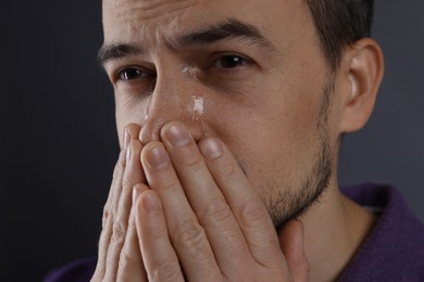 Photo of Sad man crying on grey background, closeup