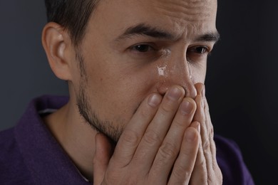 Sad man crying on grey background, closeup