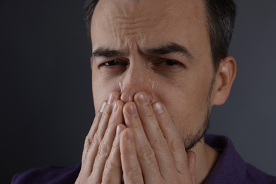 Sad man crying on grey background, closeup