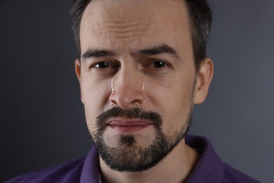 Photo of Sad man crying on grey background, closeup