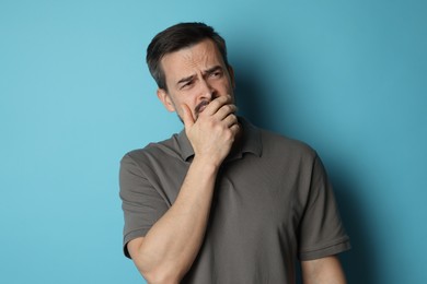 Sad man crying on light blue background