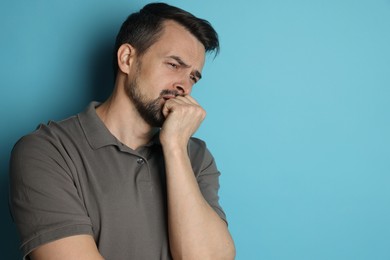 Sad man crying on light blue background, space for text