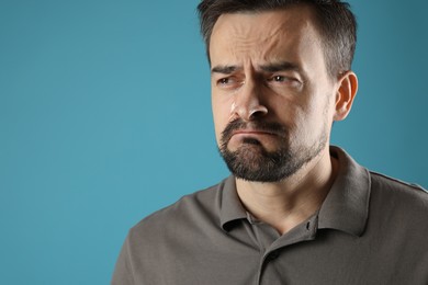 Photo of Sad man crying on light blue background, space for text