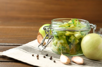 Photo of Delicious green salsa in jar and ingredients on wooden table, closeup. Space for text