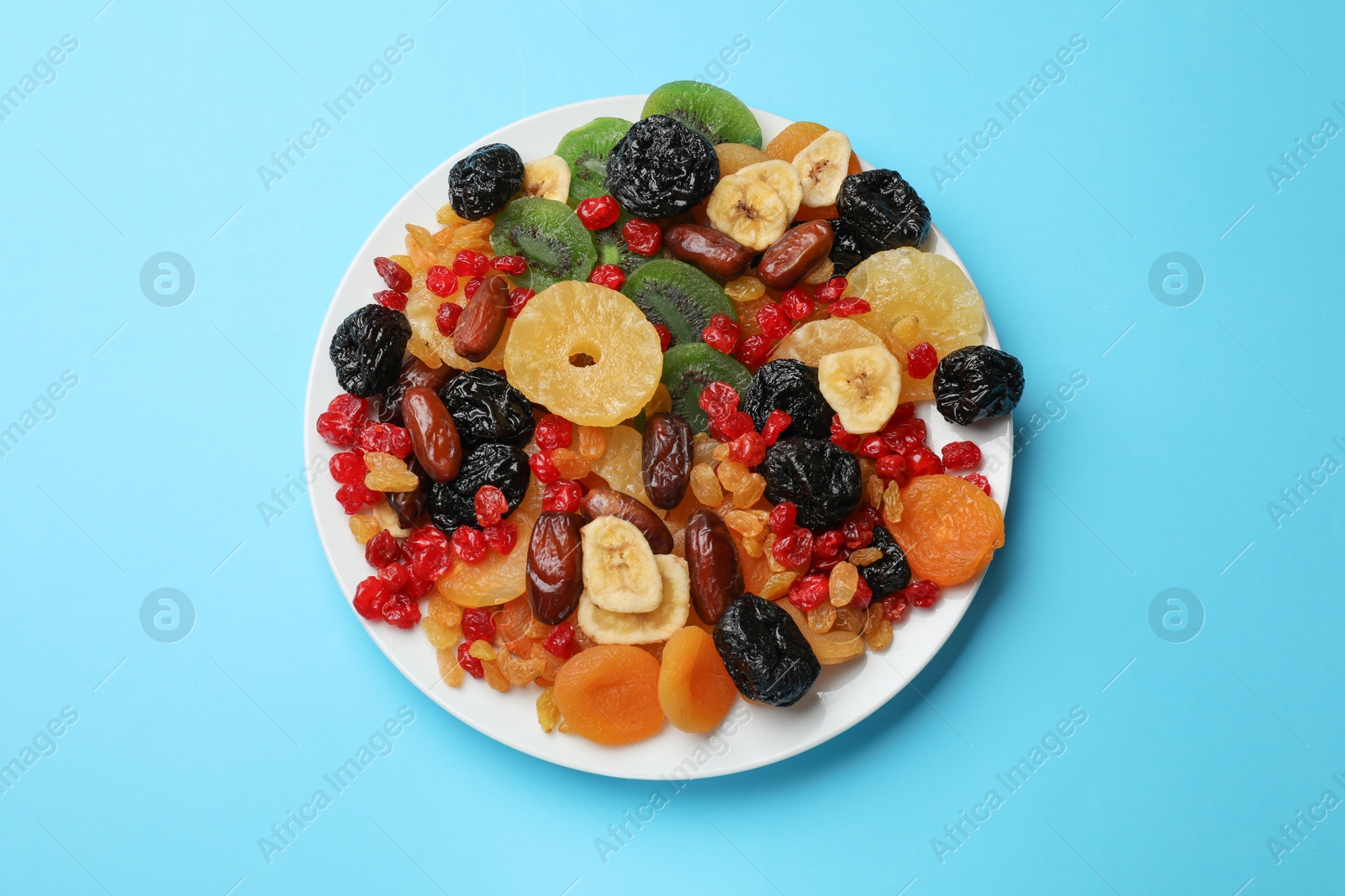 Photo of Mix of different dried fruits on light blue background, top view