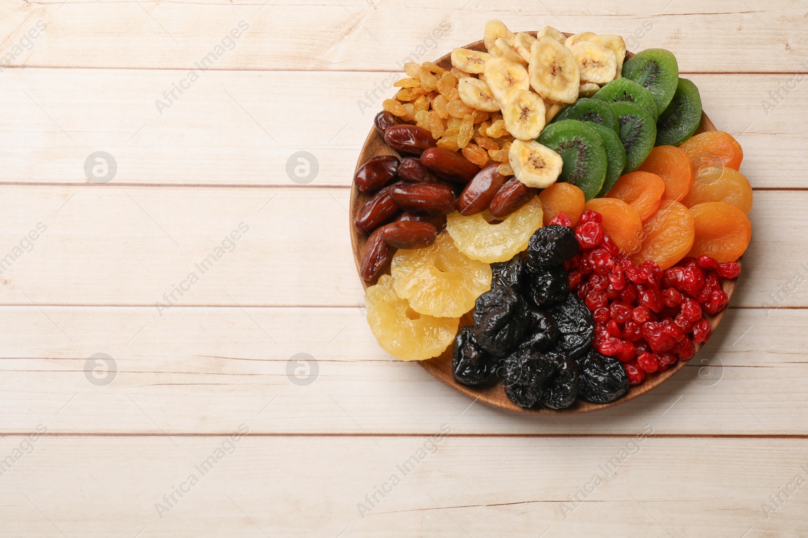 Photo of Different dried fruits on white wooden table, top view. Space for text