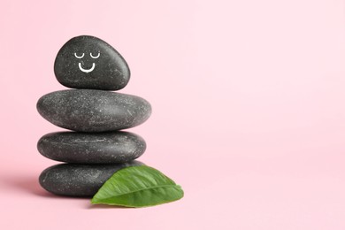 Photo of Stack of rocks with drawn smiley face on light pink background, space for text. Harmony and life balance