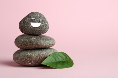 Photo of Stack of rocks with drawn smiley face on light pink background, space for text. Harmony and life balance