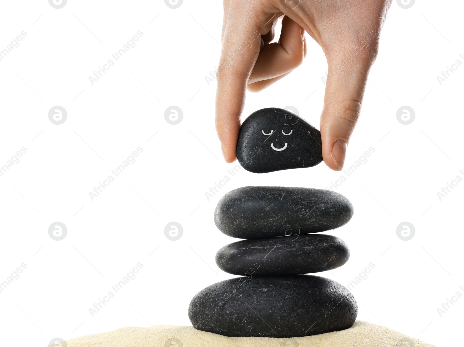 Photo of Woman putting stone with drawn smiley face on stack against white background, closeup. Harmony and life balance