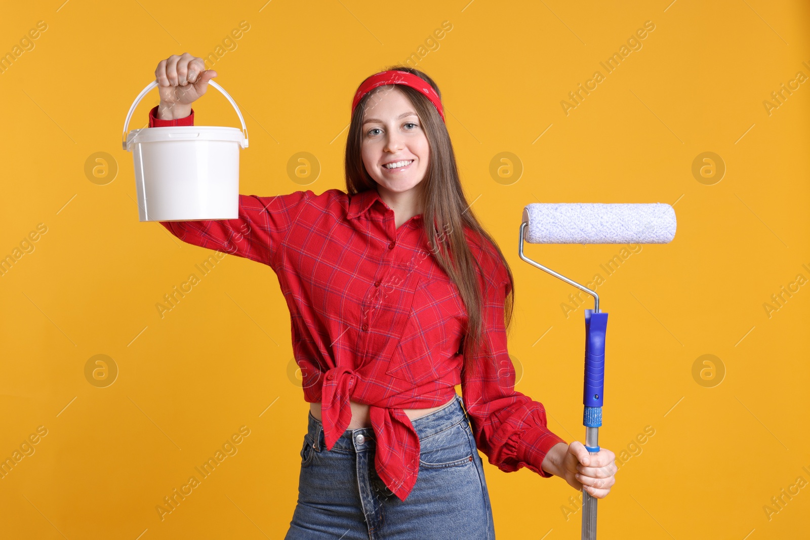 Photo of Woman with roller and bucket of paint on orange background