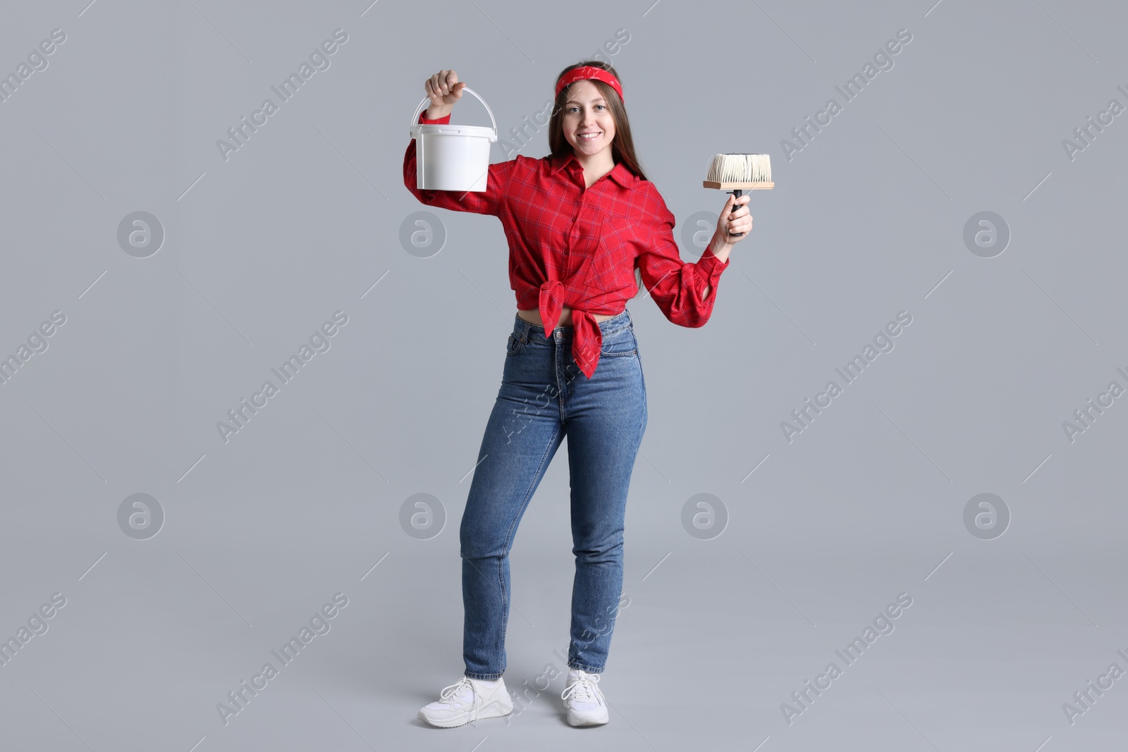 Photo of Woman with brush and bucket of paint on light grey background