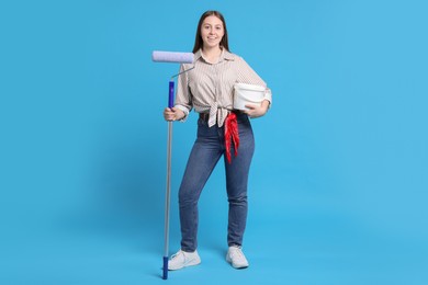 Woman with roller and bucket of paint on light blue background