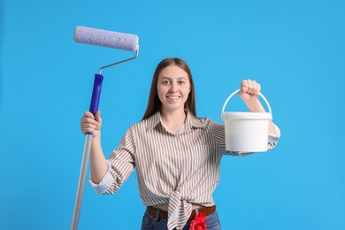 Photo of Woman with roller and bucket of paint on light blue background