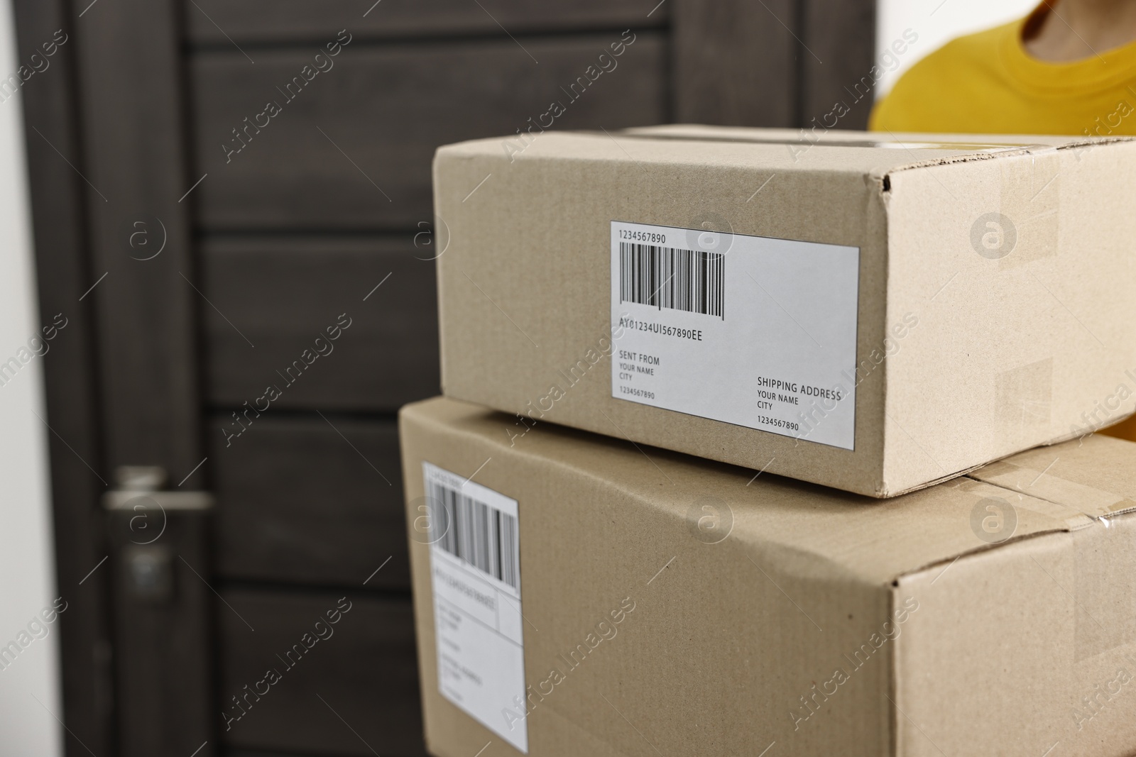 Photo of Man holding parcels with shipping labels near door indoors, closeup. Space for text