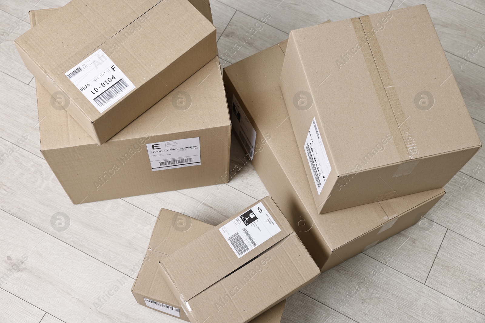 Photo of Cardboard parcel boxes with shipping labels on floor indoors, top view