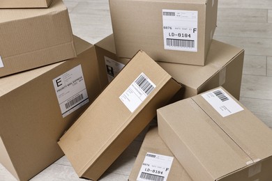 Cardboard parcel boxes with shipping labels on floor indoors, closeup