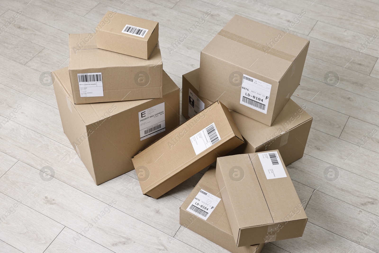 Photo of Cardboard parcel boxes with shipping labels on floor indoors