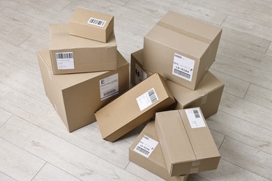 Photo of Cardboard parcel boxes with shipping labels on floor indoors