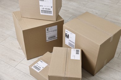 Photo of Cardboard parcel boxes with shipping labels on floor indoors