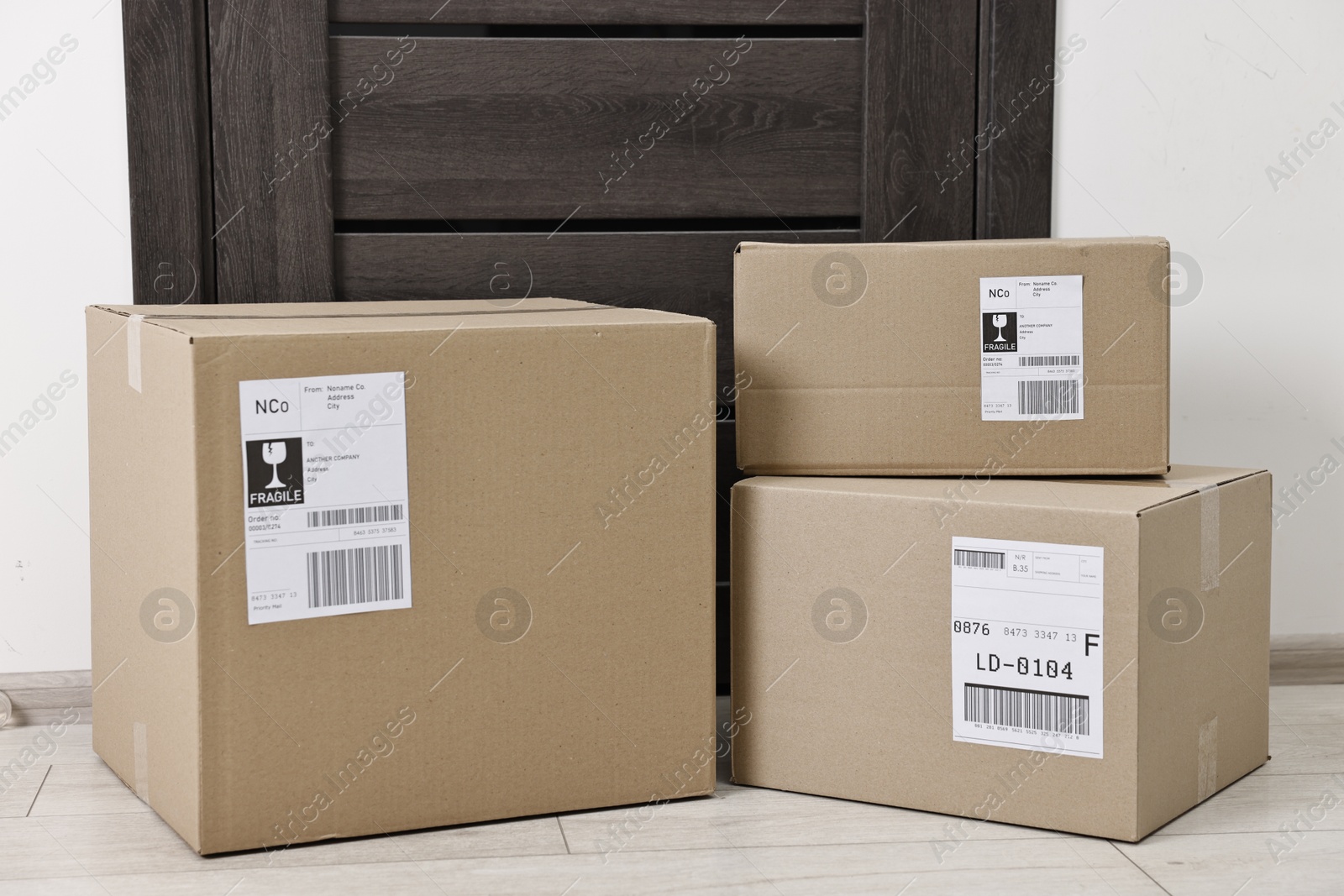 Photo of Cardboard parcel boxes with shipping labels near door indoors