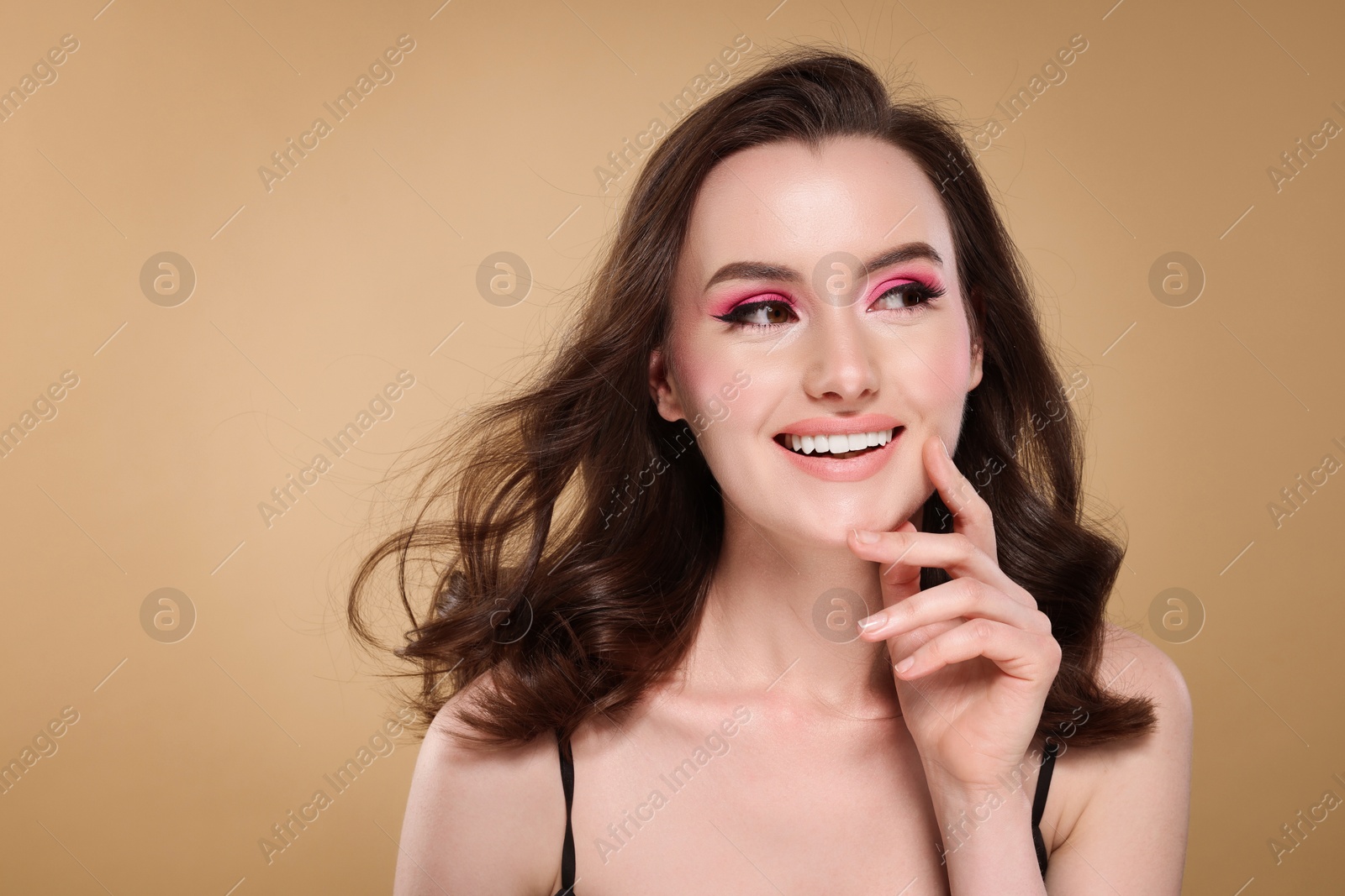 Photo of Portrait of beautiful young woman with stylish makeup and gorgeous hair on beige background. Space for text