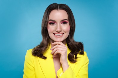 Portrait of beautiful young woman with stylish makeup and gorgeous hair on light blue background