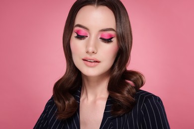 Photo of Portrait of beautiful young woman with stylish makeup and gorgeous hair on pink background