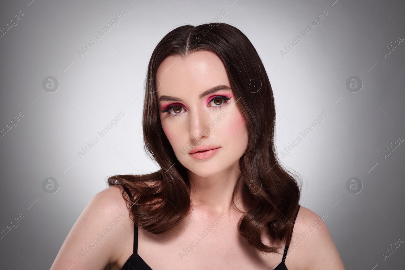 Photo of Portrait of beautiful young woman with stylish makeup and gorgeous hair on light grey background