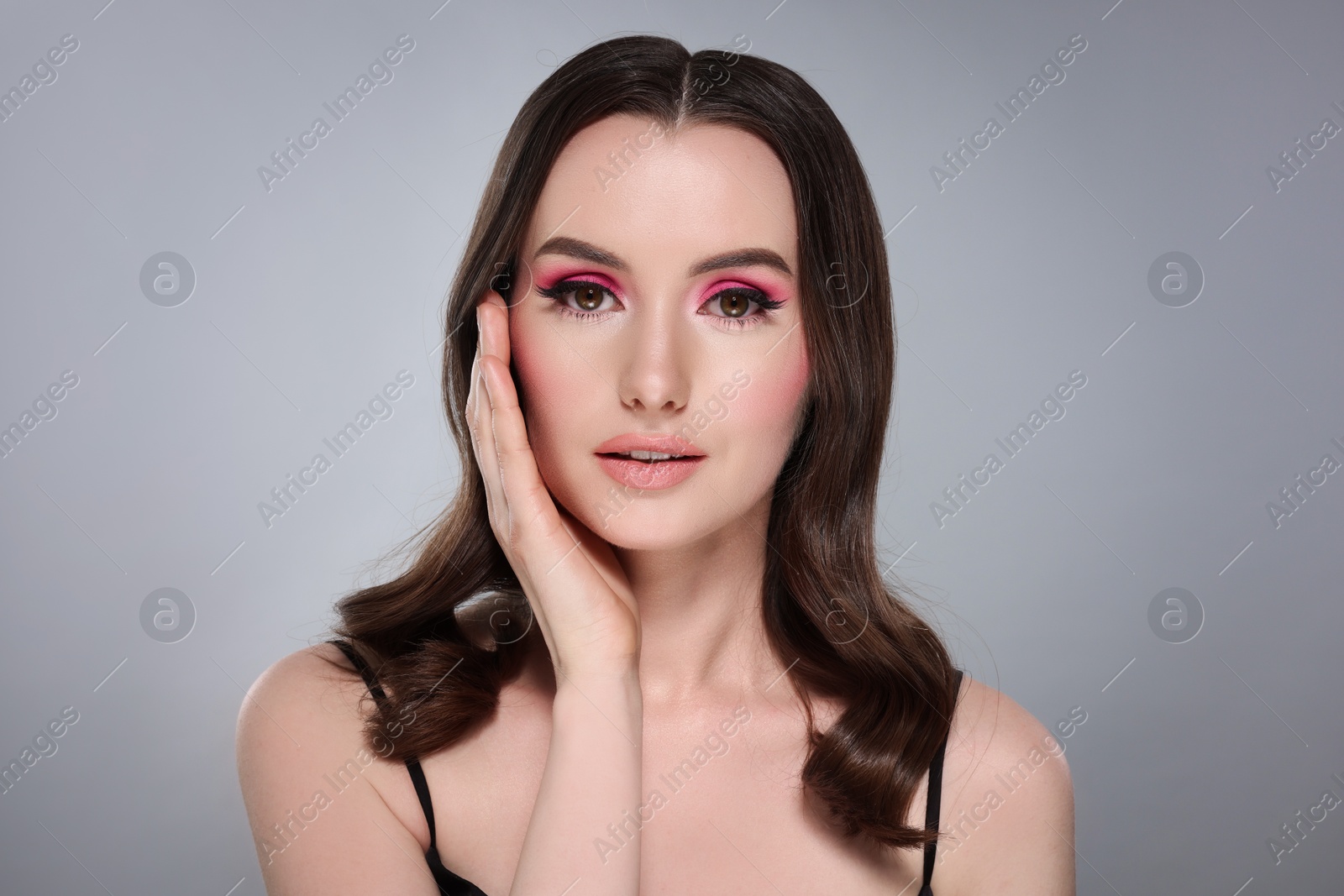 Photo of Portrait of beautiful young woman with stylish makeup and gorgeous hair on light grey background