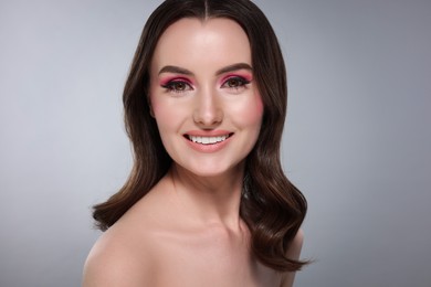 Portrait of beautiful young woman with stylish makeup and gorgeous hair on light grey background