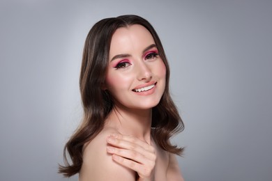 Photo of Portrait of beautiful young woman with stylish makeup and gorgeous hair on light grey background