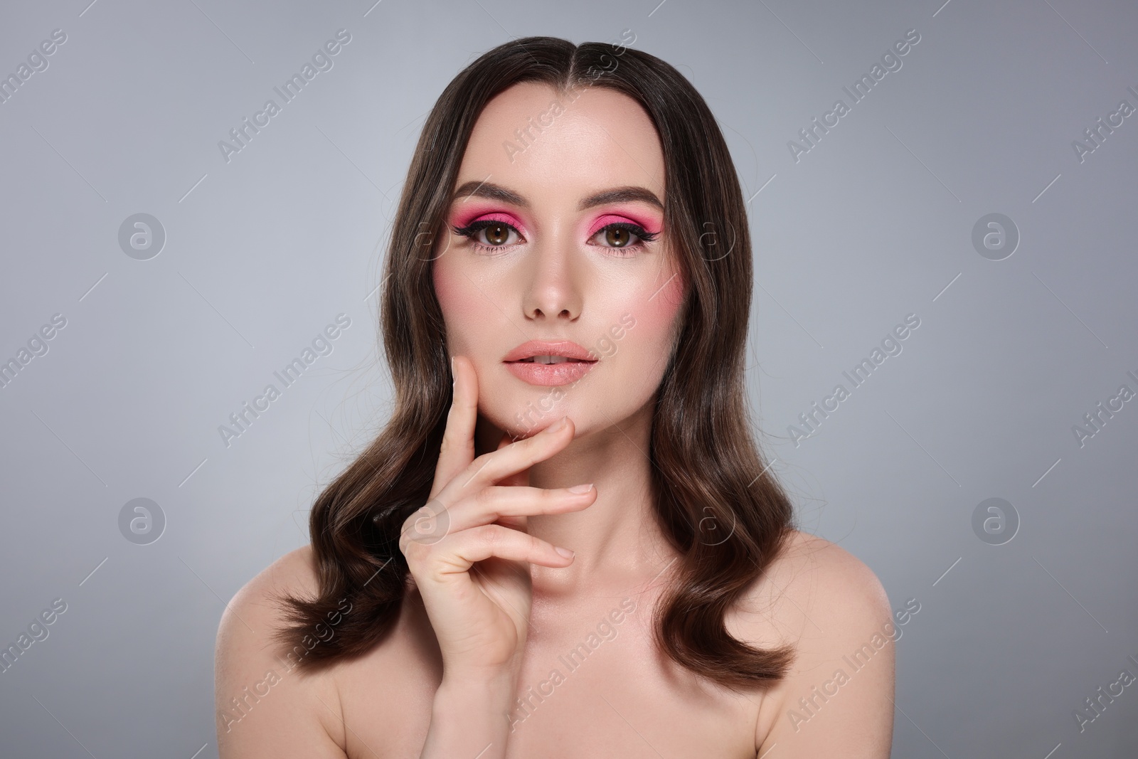 Photo of Portrait of beautiful young woman with stylish makeup and gorgeous hair on light grey background