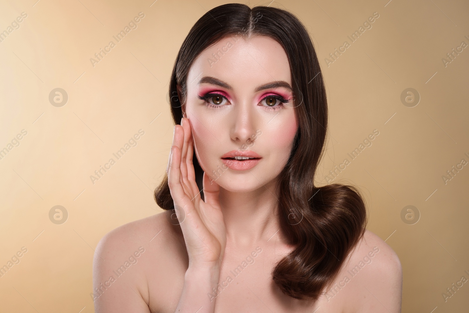 Photo of Portrait of beautiful young woman with stylish makeup and gorgeous hair on beige background