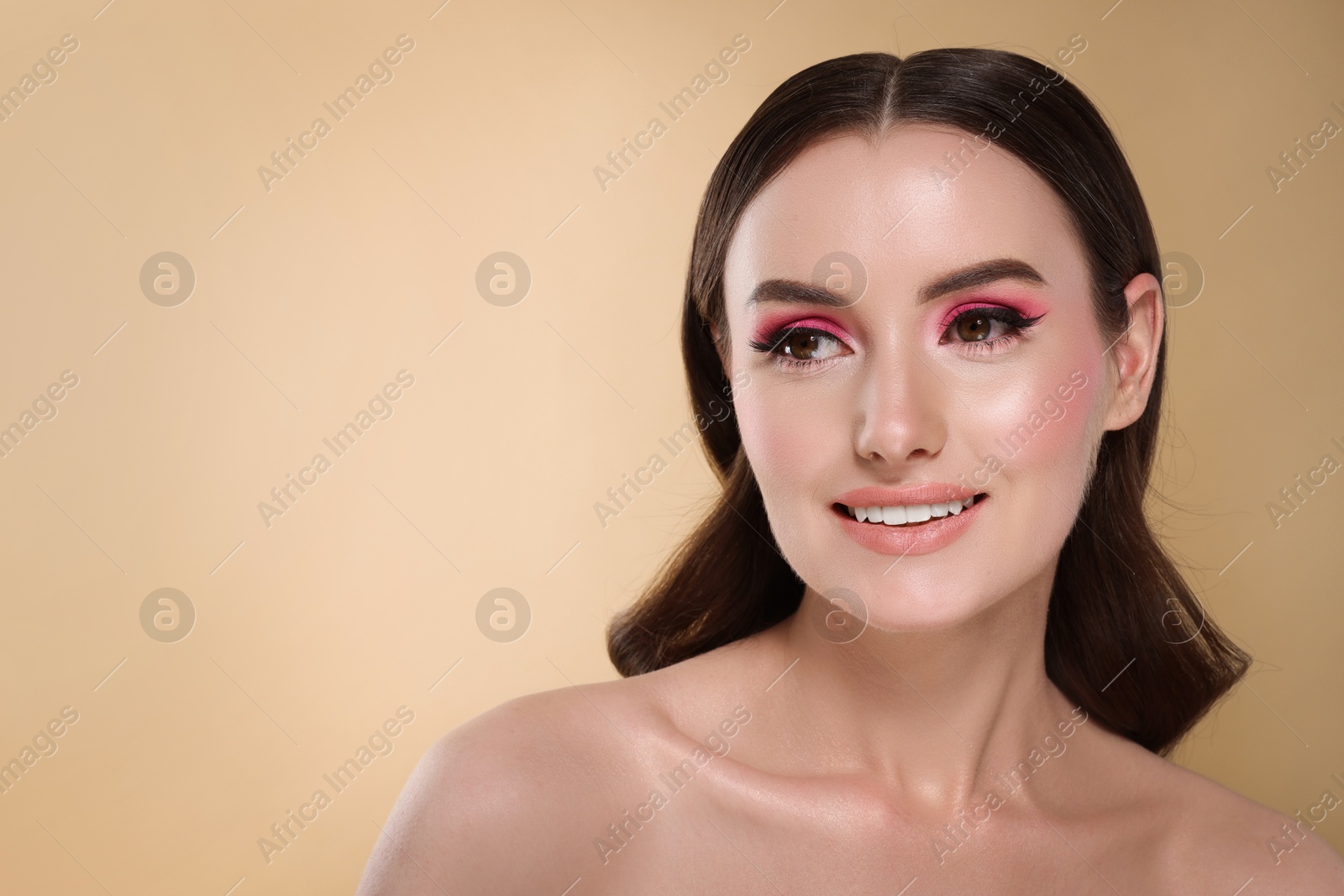 Photo of Portrait of beautiful young woman with stylish makeup and gorgeous hair on beige background. Space for text